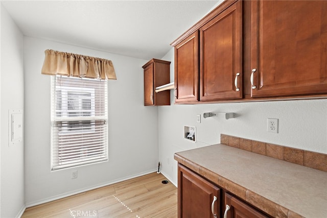 laundry room with cabinet space, washer hookup, light wood-type flooring, and baseboards