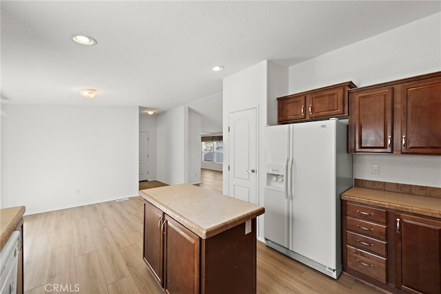 kitchen featuring white refrigerator with ice dispenser, light wood-style flooring, a kitchen island, and recessed lighting