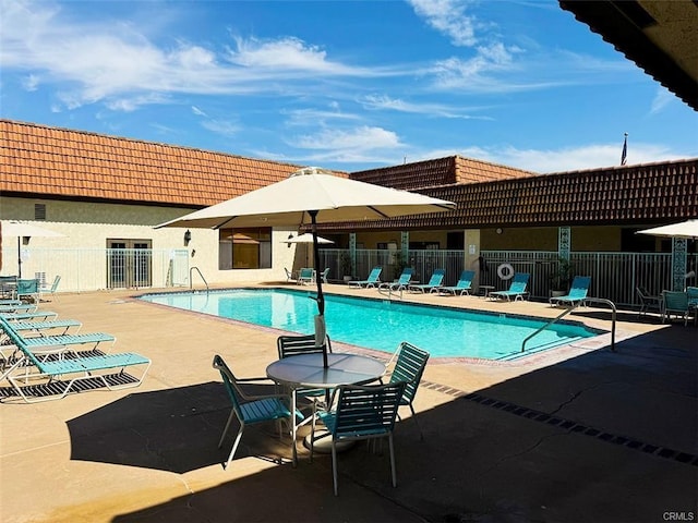community pool with fence and a patio