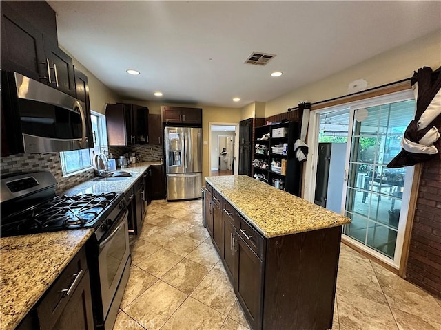 6127 Adenmoor Ave, Lakewood, CA 90713 - kitchen featuring appliances with stainless steel finishes, a sink, tasteful backsplash, a center island, and light stone counters