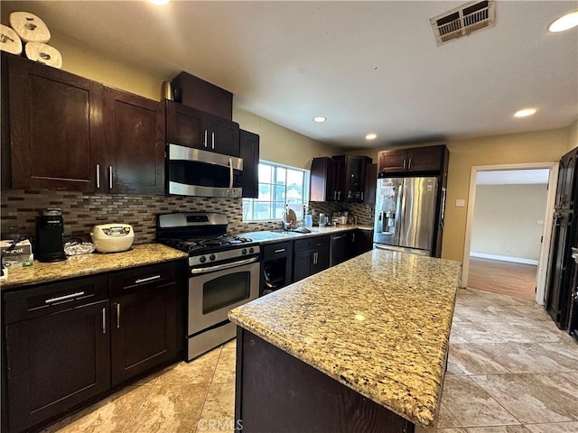 6127 Adenmoor Ave, Lakewood, CA 90713 - kitchen featuring appliances with stainless steel finishes, decorative backsplash, light stone countertops, a sink, and recessed lighting