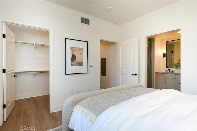 414 Main Unit 200, Huntington Beach, CA 92648 - bedroom featuring wood finished floors, a walk in closet, a closet, baseboards, and ensuite bath