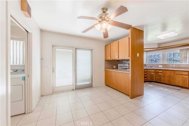 kitchen with washer / dryer, light countertops, ceiling fan, backsplash, and brown cabinetry