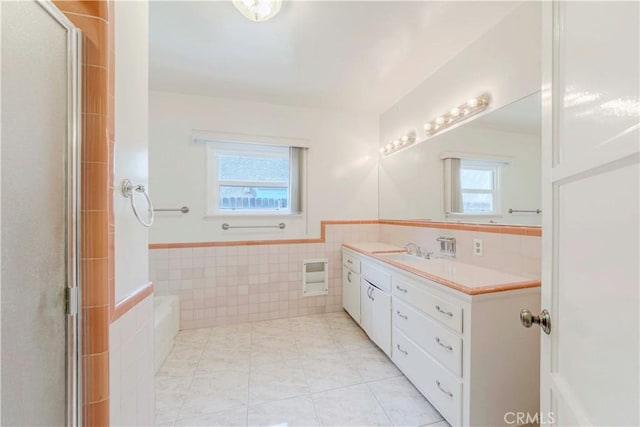 full bath with tile walls, vanity, a wainscoted wall, a shower with door, and tile patterned floors