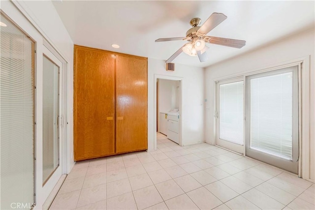 unfurnished bedroom with access to exterior, washer / clothes dryer, a ceiling fan, and light tile patterned flooring