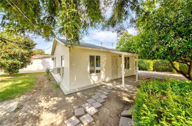 rear view of property with stucco siding and a patio