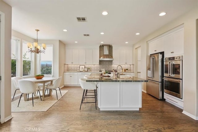27086 Maple Tree Ct, Valencia, CA 91381 - kitchen featuring stainless steel appliances, wall chimney exhaust hood, white cabinetry, tasteful backsplash, and recessed lighting