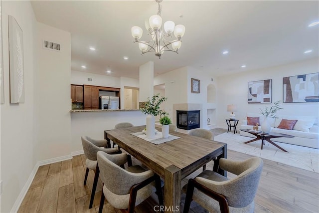 28220 Highridge Rd Unit 104, Rancho Palos Verdes, CA 90275 - dining room with light wood-style flooring, a multi sided fireplace, a chandelier, baseboards, and recessed lighting