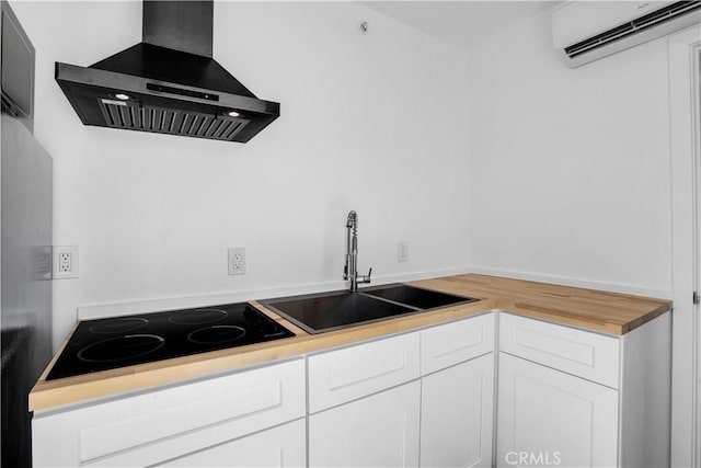 72473 Desert Trail Dr Unit 29, Palms, CA 92277 - kitchen featuring wall chimney exhaust hood, a wall mounted air conditioner, black electric cooktop, white cabinets, and a sink