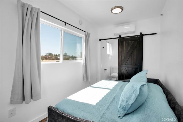 72473 Desert Trail Dr Unit 29, Palms, CA 92277 - bedroom with a wall mounted AC, a barn door, ensuite bath, and baseboards