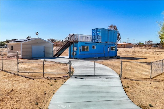 72473 Desert Trail Dr Unit 29, Palms, CA 92277 - view of front of house featuring concrete driveway, a detached garage, an outbuilding, a fenced front yard, and a gate