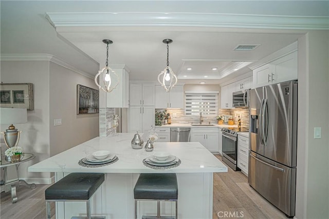3365 Punta Alta Unit 3C, Laguna Woods, CA 92637 - kitchen with appliances with stainless steel finishes, a sink, white cabinetry, light wood-type flooring, and a breakfast bar area