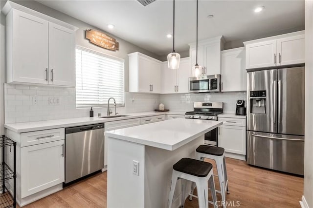 16073 Narni Ln, Fontana, CA 92336 - kitchen with appliances with stainless steel finishes, a sink, white cabinets, a kitchen breakfast bar, and recessed lighting
