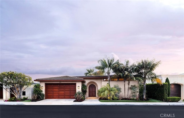 1131 Dolphin Ter, Corona Del Mar, CA 92625 - mediterranean / spanish-style home featuring an attached garage, stucco siding, and driveway
