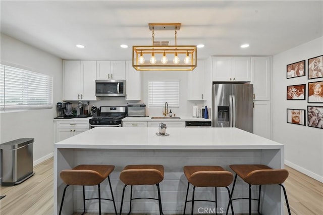 1343 Cordon Dr, City Terrace, CA 90063 - kitchen with stainless steel appliances, a kitchen bar, white cabinetry, light wood-type flooring, and recessed lighting