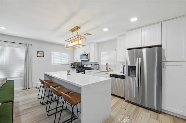 1343 Cordon Dr, City Terrace, CA 90063 - kitchen with appliances with stainless steel finishes, a center island, a breakfast bar, white cabinets, and recessed lighting
