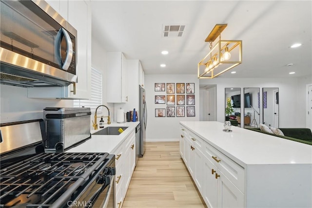 1343 Cordon Dr, City Terrace, CA 90063 - kitchen with stainless steel appliances, white cabinets, recessed lighting, light wood-style flooring, and light countertops