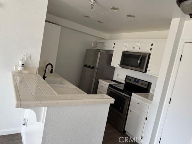 11410 Dolan Ave Unit 227, Downey, CA 90241 - kitchen featuring appliances with stainless steel finishes, a peninsula, tile countertops, a sink, and dark wood-style flooring