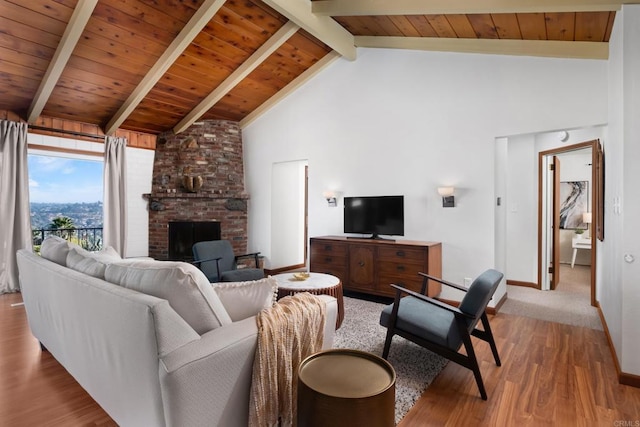 living room featuring beamed ceiling, wood finished floors, high vaulted ceiling, a fireplace, and baseboards