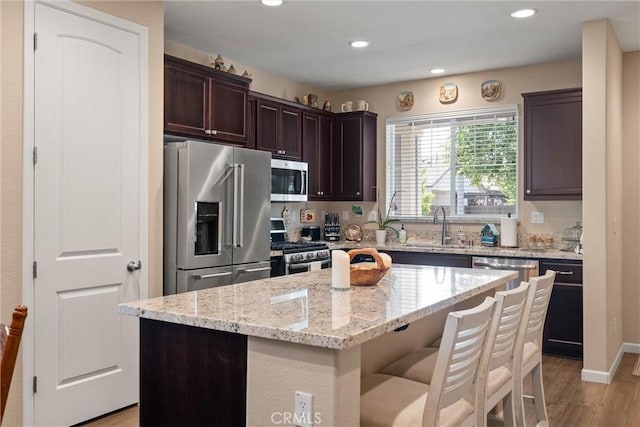 3293 Rogue River Dr, Chico, CA 95973 - kitchen featuring stainless steel appliances, a center island, dark brown cabinets, light wood-style floors, and a sink