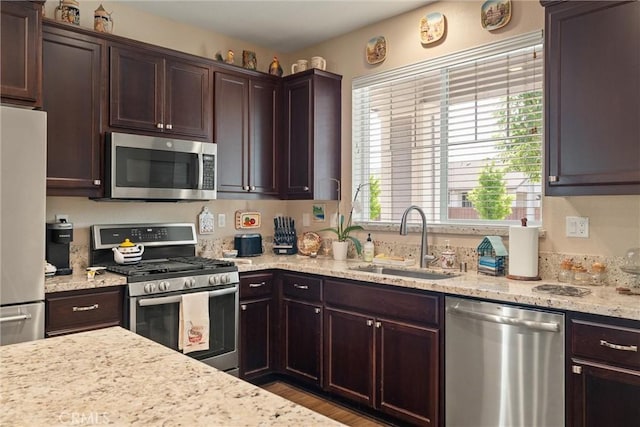 3293 Rogue River Dr, Chico, CA 95973 - kitchen featuring appliances with stainless steel finishes, a sink, dark brown cabinets, light stone counters, and wood finished floors