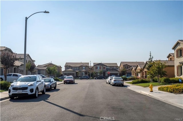 15590 Pumpkin Pl, Fontana, CA 92336 - view of asphalt road with sidewalks, a residential view, street lighting, and curbs