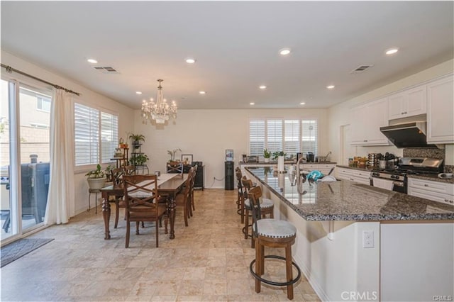 15590 Pumpkin Pl, Fontana, CA 92336 - kitchen with stainless steel gas range, recessed lighting, white cabinetry, a sink, and under cabinet range hood