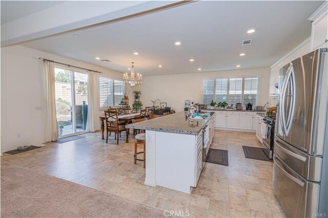15590 Pumpkin Pl, Fontana, CA 92336 - kitchen featuring freestanding refrigerator, gas stove, white cabinets, a kitchen breakfast bar, and a kitchen island