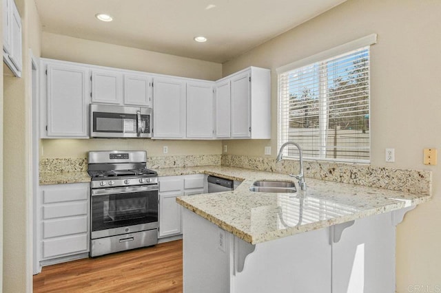 2550 Garnet Peak Rd, Chula Vista, CA 91915 - kitchen featuring appliances with stainless steel finishes, a peninsula, a sink, light stone countertops, and white cabinets