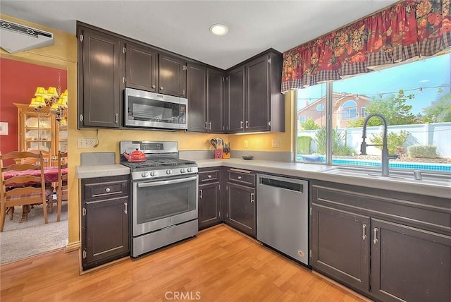6730 Harrington Ct, Chino, CA 91710 - kitchen featuring appliances with stainless steel finishes, a sink, light countertops, light wood-style floors, and an AC wall unit