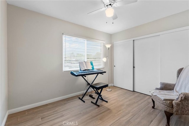 sitting room with light wood-style floors, a ceiling fan, and baseboards