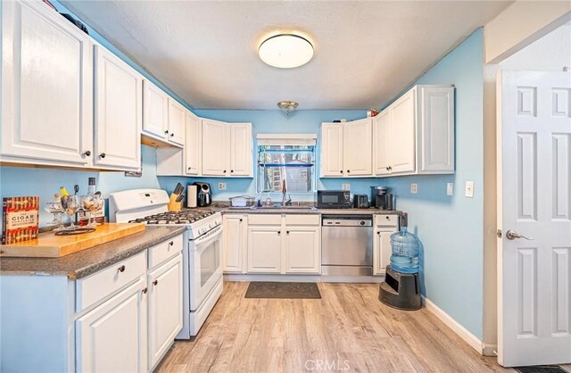 23120 Sycamore Ln, Crestline, CA 92325 - kitchen featuring stainless steel dishwasher, white gas range oven, black microwave, light wood-style flooring, and white cabinetry
