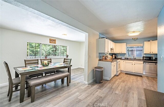 23120 Sycamore Ln, Crestline, CA 92325 - kitchen featuring stainless steel dishwasher, white gas range, light wood finished floors, dark countertops, and black microwave