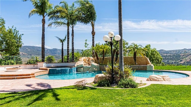 view of swimming pool featuring a mountain view, a pool with connected hot tub, and a patio area