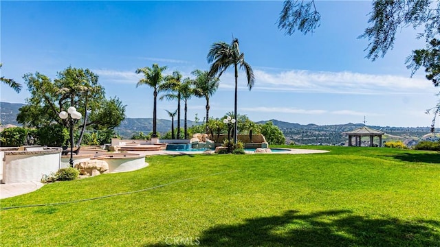 view of property's community with a gazebo, a yard, a pool, and a mountain view