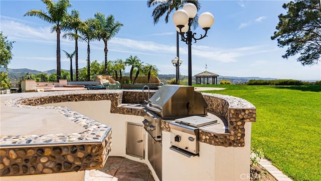 view of patio with exterior kitchen, grilling area, and a mountain view