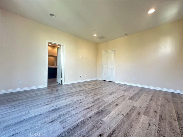 empty room featuring wood finished floors, baseboards, and recessed lighting