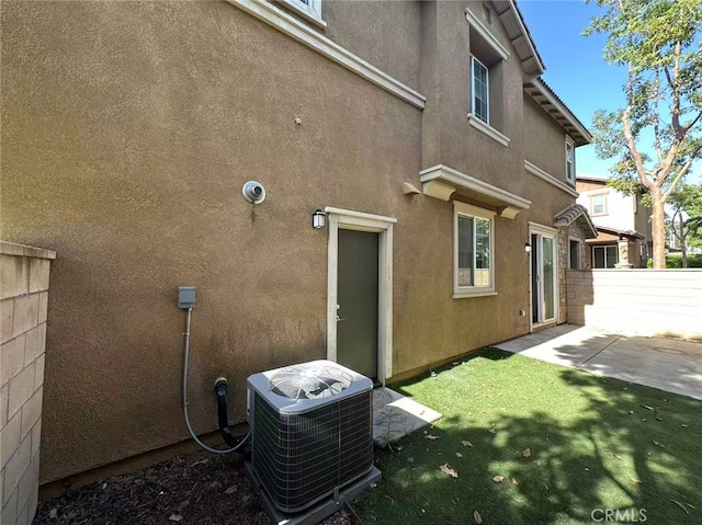 view of side of home featuring cooling unit, stucco siding, and a patio area