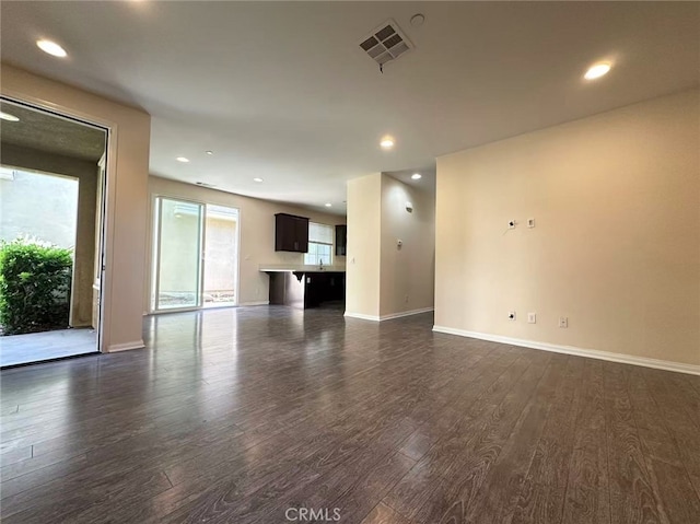 unfurnished living room with dark wood-style flooring, baseboards, and recessed lighting