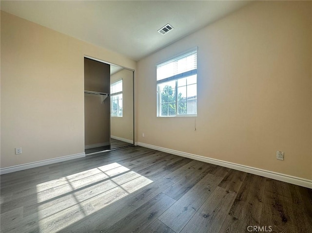 unfurnished bedroom with baseboards, dark wood-type flooring, and a closet