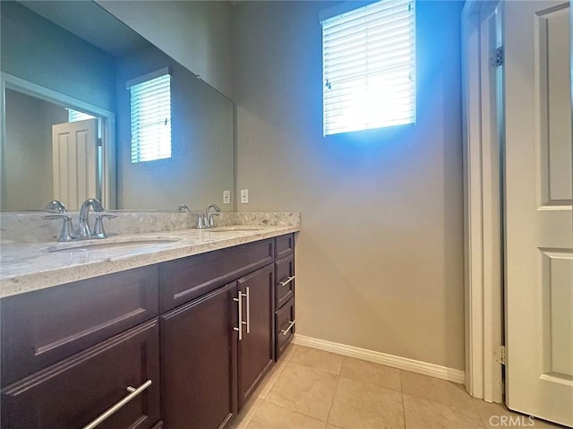 bathroom with baseboards, double vanity, and tile patterned floors