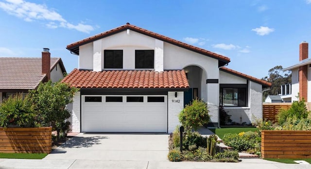 mediterranean / spanish-style home featuring a tile roof, concrete driveway, stucco siding, and a garage