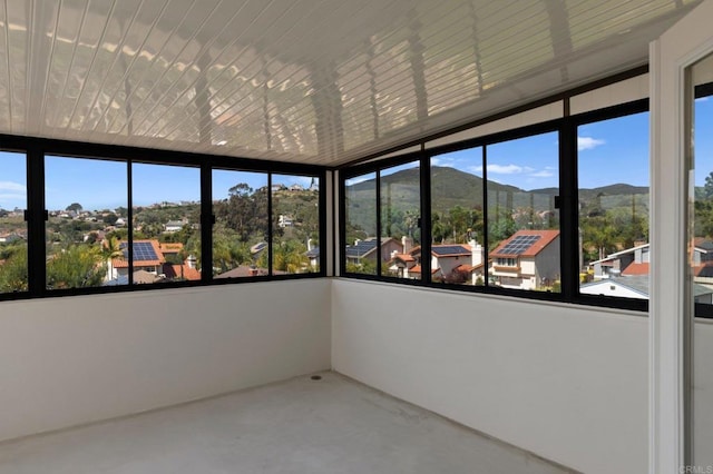 unfurnished sunroom featuring a mountain view and concrete flooring