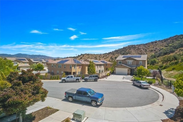 view of street with a mountain view, a residential view, sidewalks, and curbs