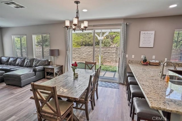 dining room with a chandelier, healthy amount of natural light, wood finished floors, and recessed lighting