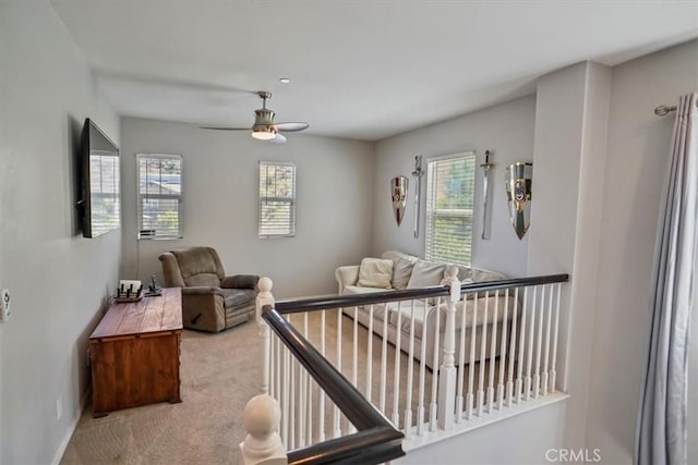 living area with carpet floors, a ceiling fan, and baseboards