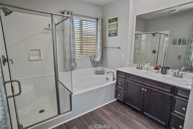 full bathroom with wood finished floors, a shower stall, a garden tub, and double vanity