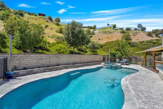 view of swimming pool featuring a fenced backyard, a pool with connected hot tub, and a patio