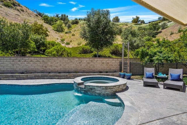 view of swimming pool with a patio area, a pool with connected hot tub, and a fenced backyard