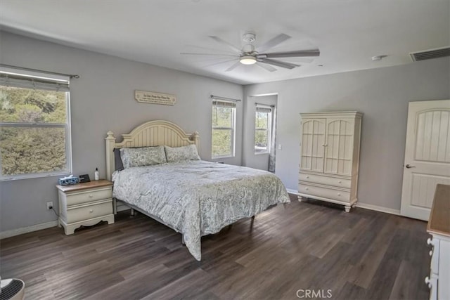 bedroom with multiple windows, dark wood-style floors, and baseboards
